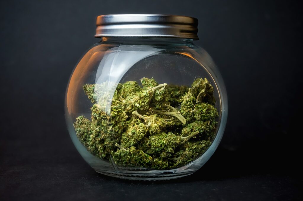 Jar with cannabis weed buds on black background